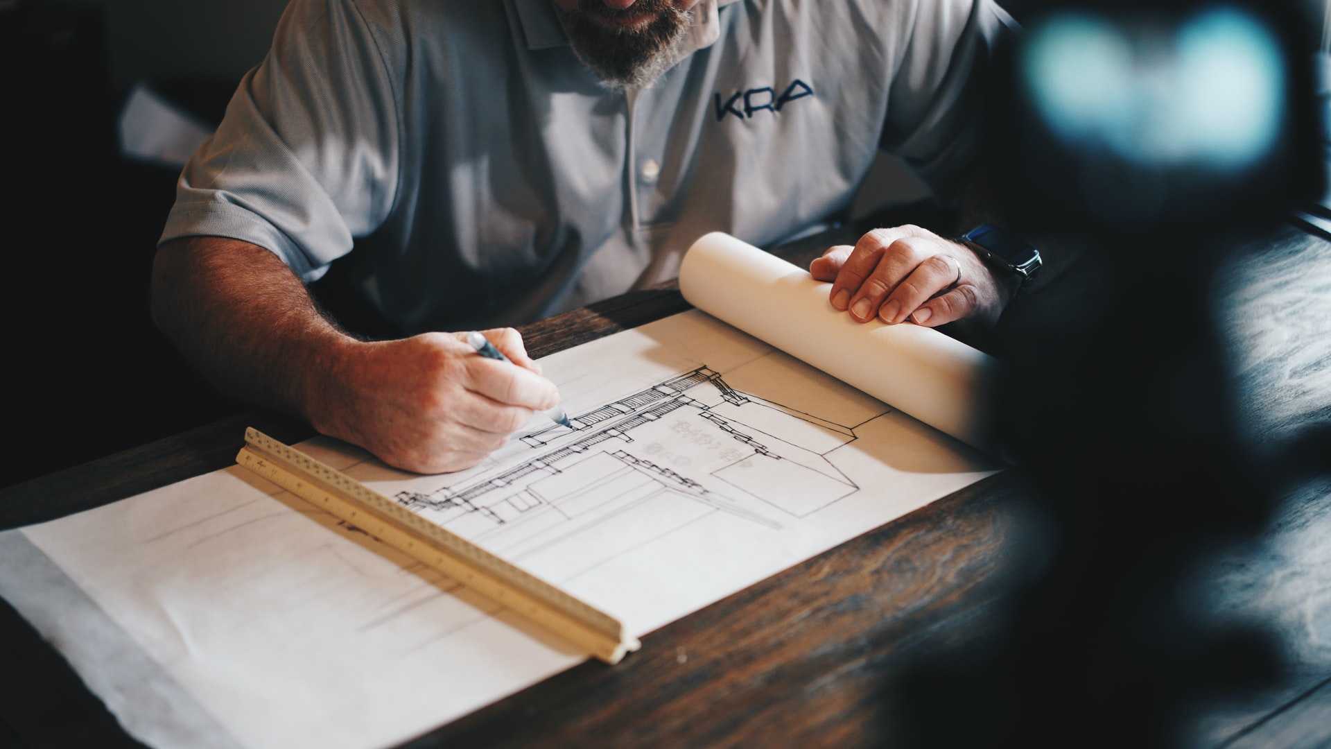 An architect draws a building on paper.
