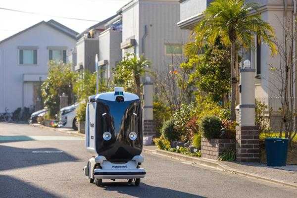 An automated delivery conveyor drives on a street in Japan.