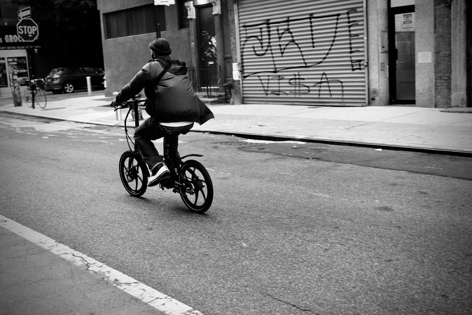 Man rides a folding bike on an empty street.