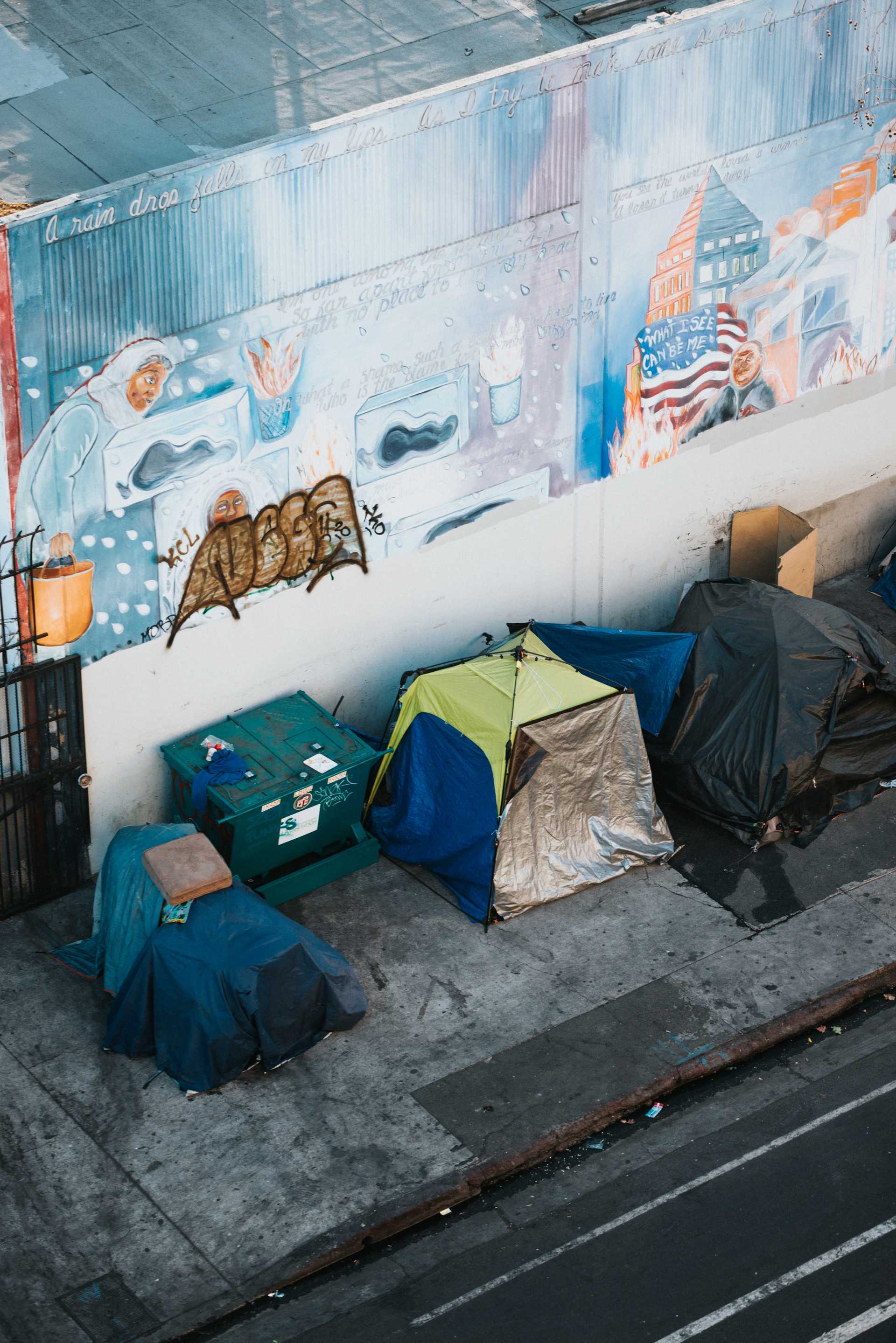 A homeless encampment of tents on a sidewalk.