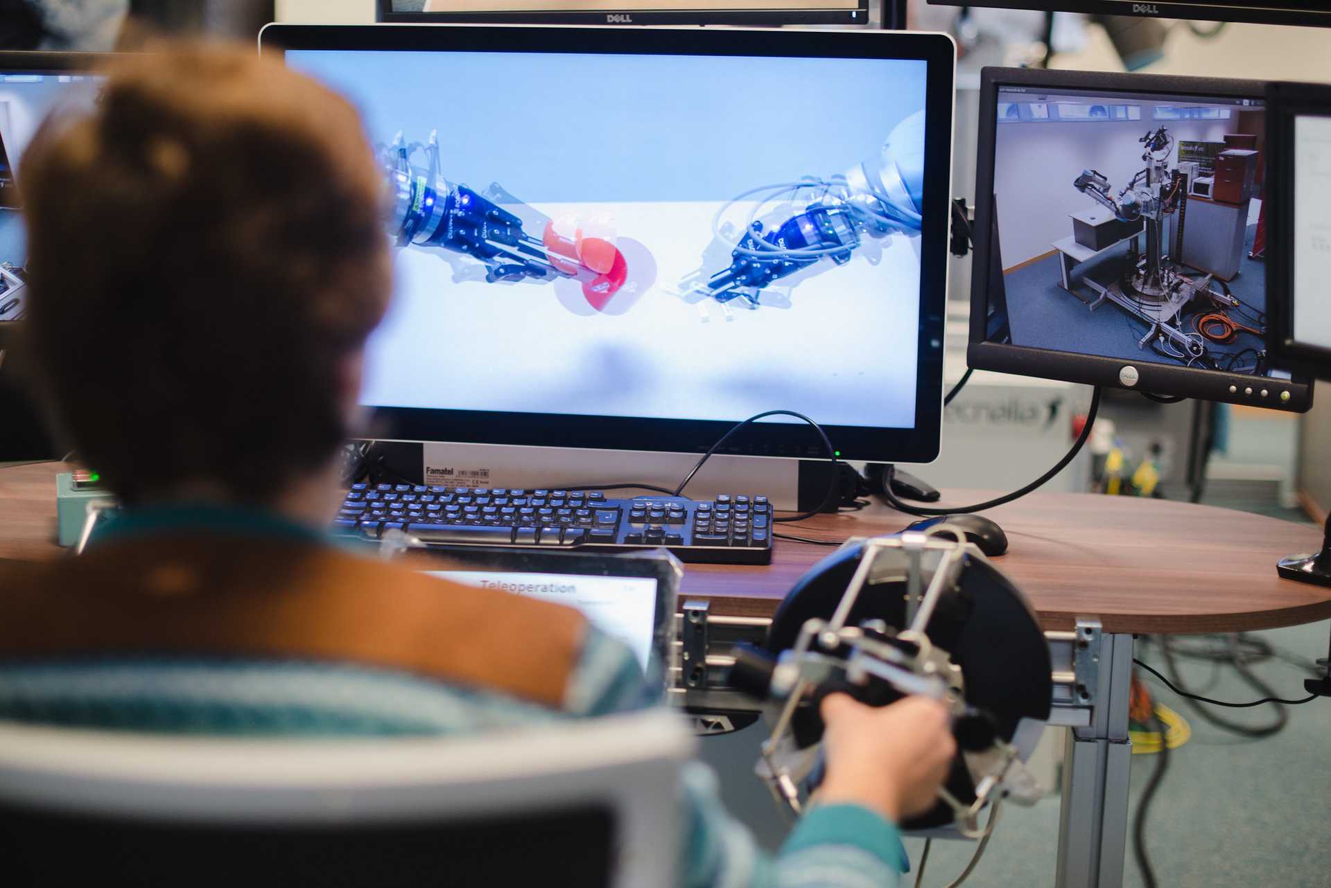 An operator controlling a remote robotic arm through a computer terminal.