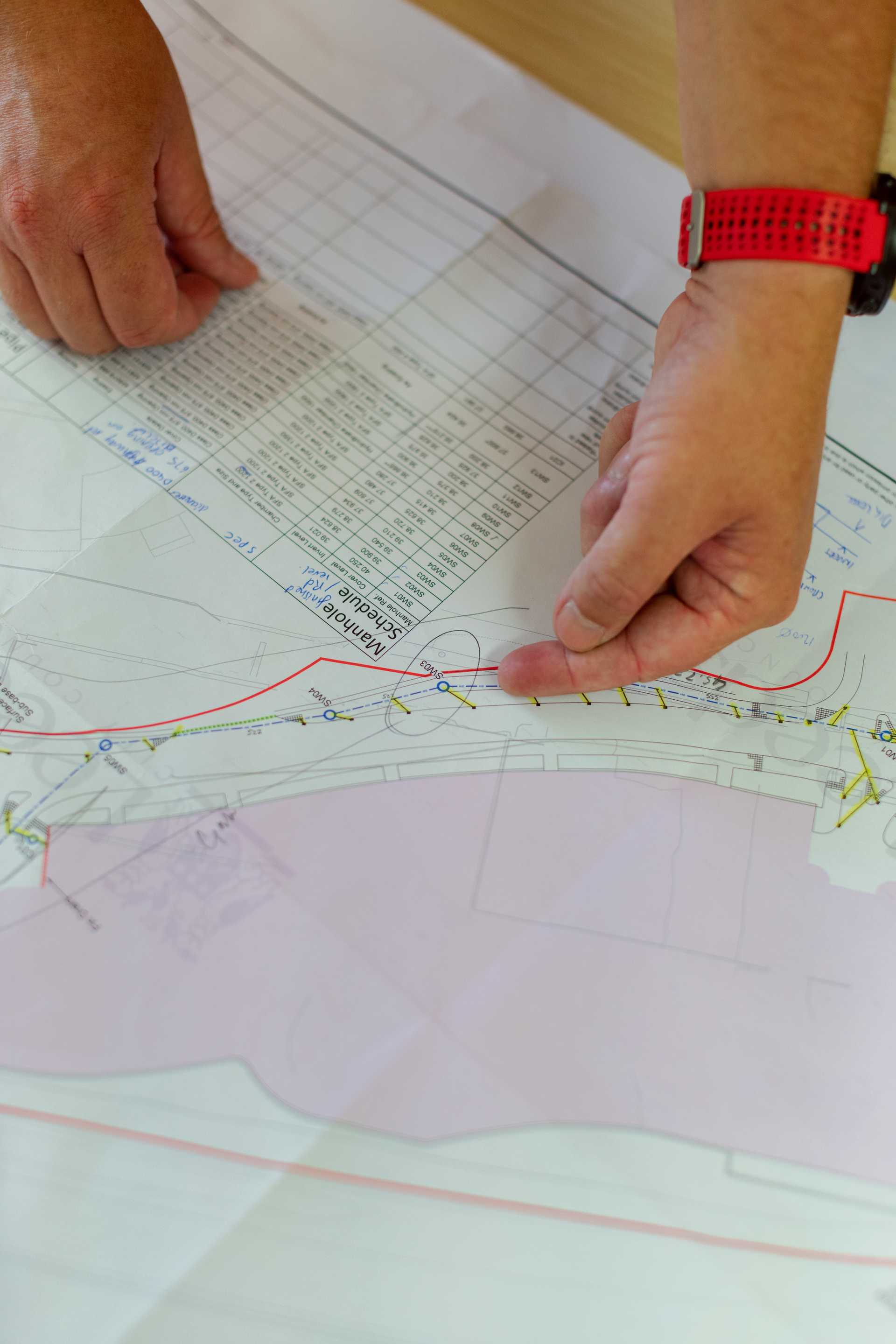 A pair of hands points out a feature on a map.