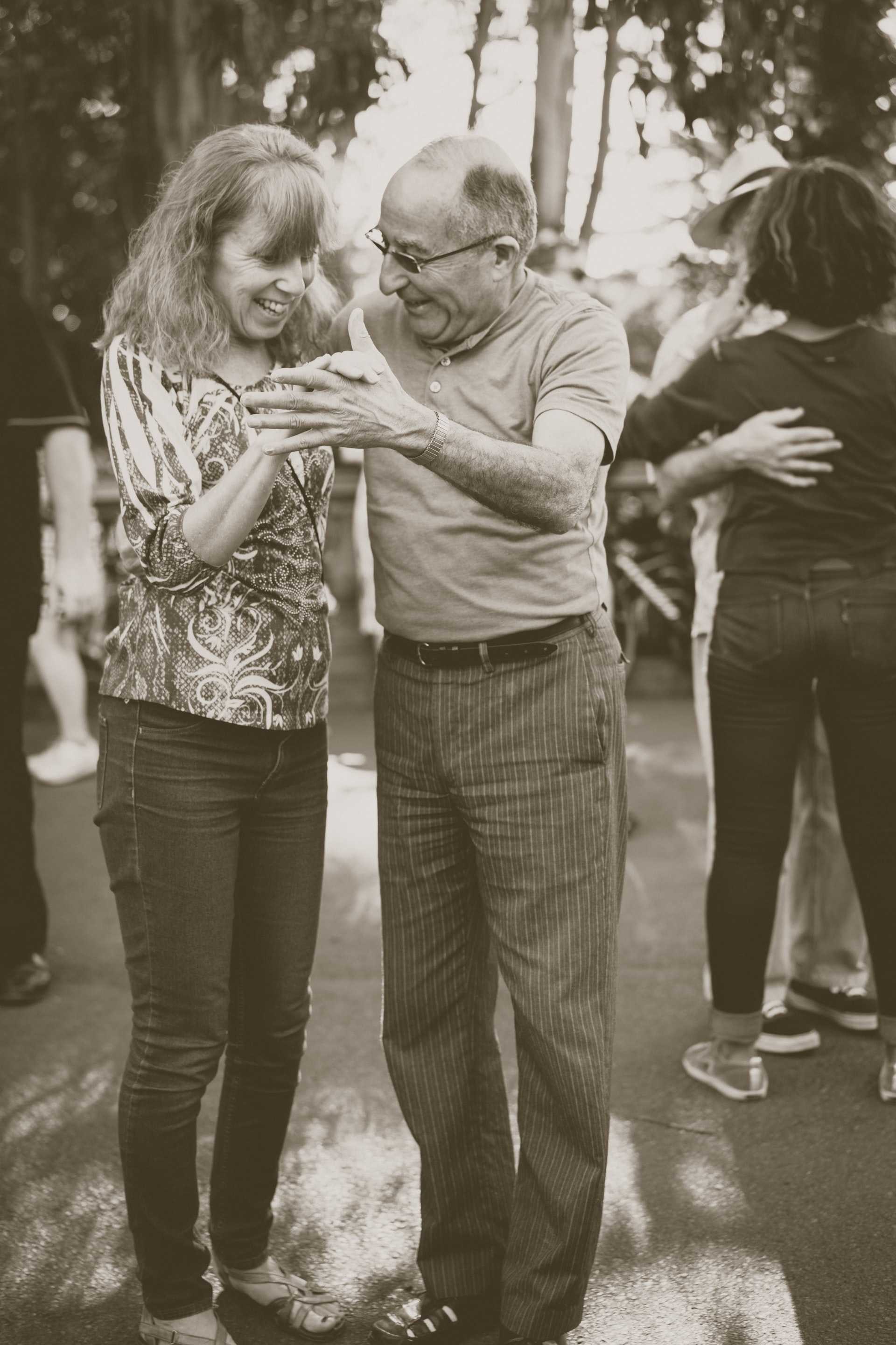 Elderly couples dance in a park.