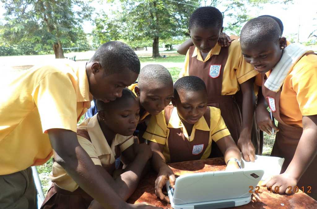 African children gather around a laptop.