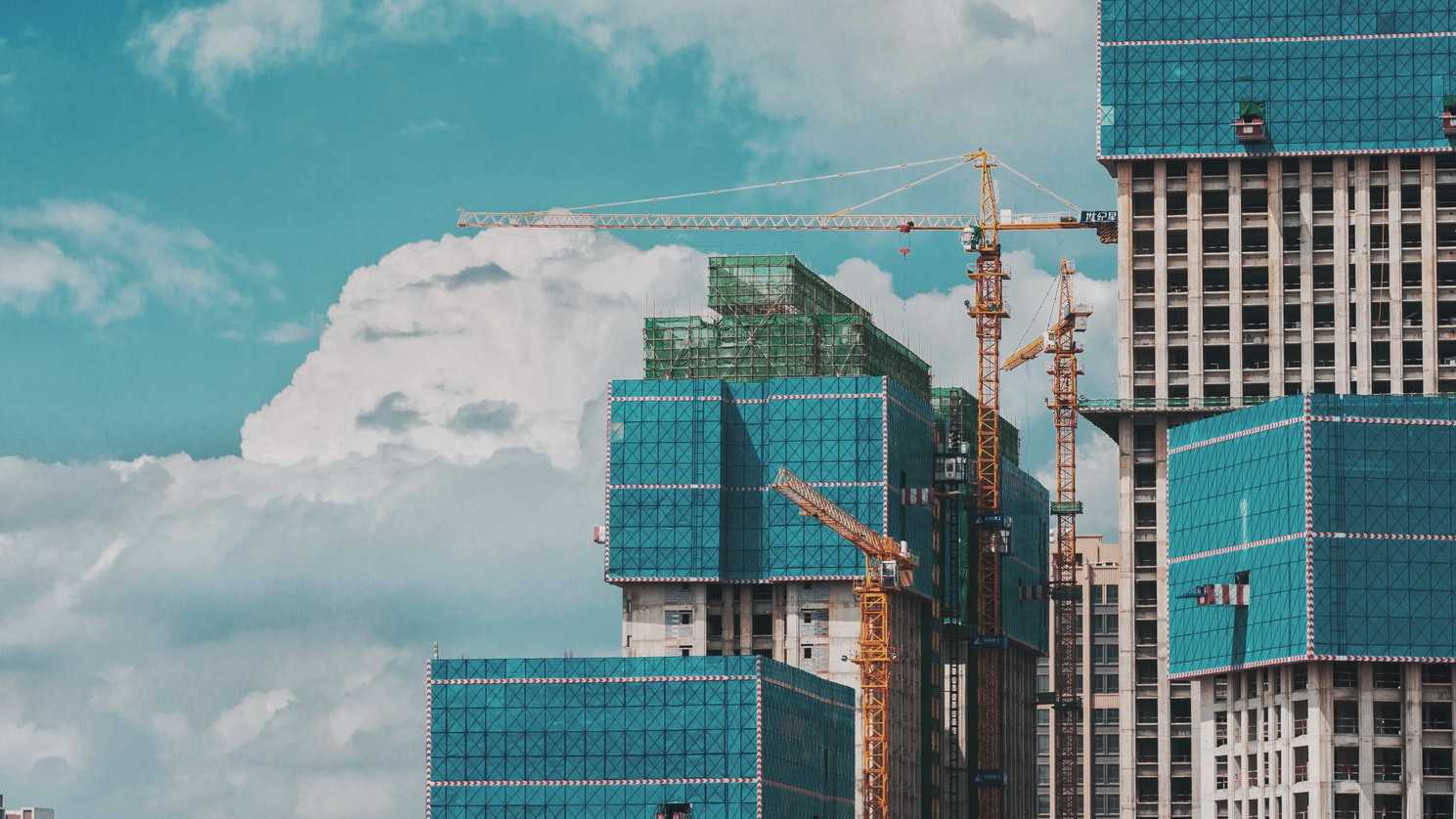 Robotic cranes perched atop a cluster of high-rise buildings under construction.