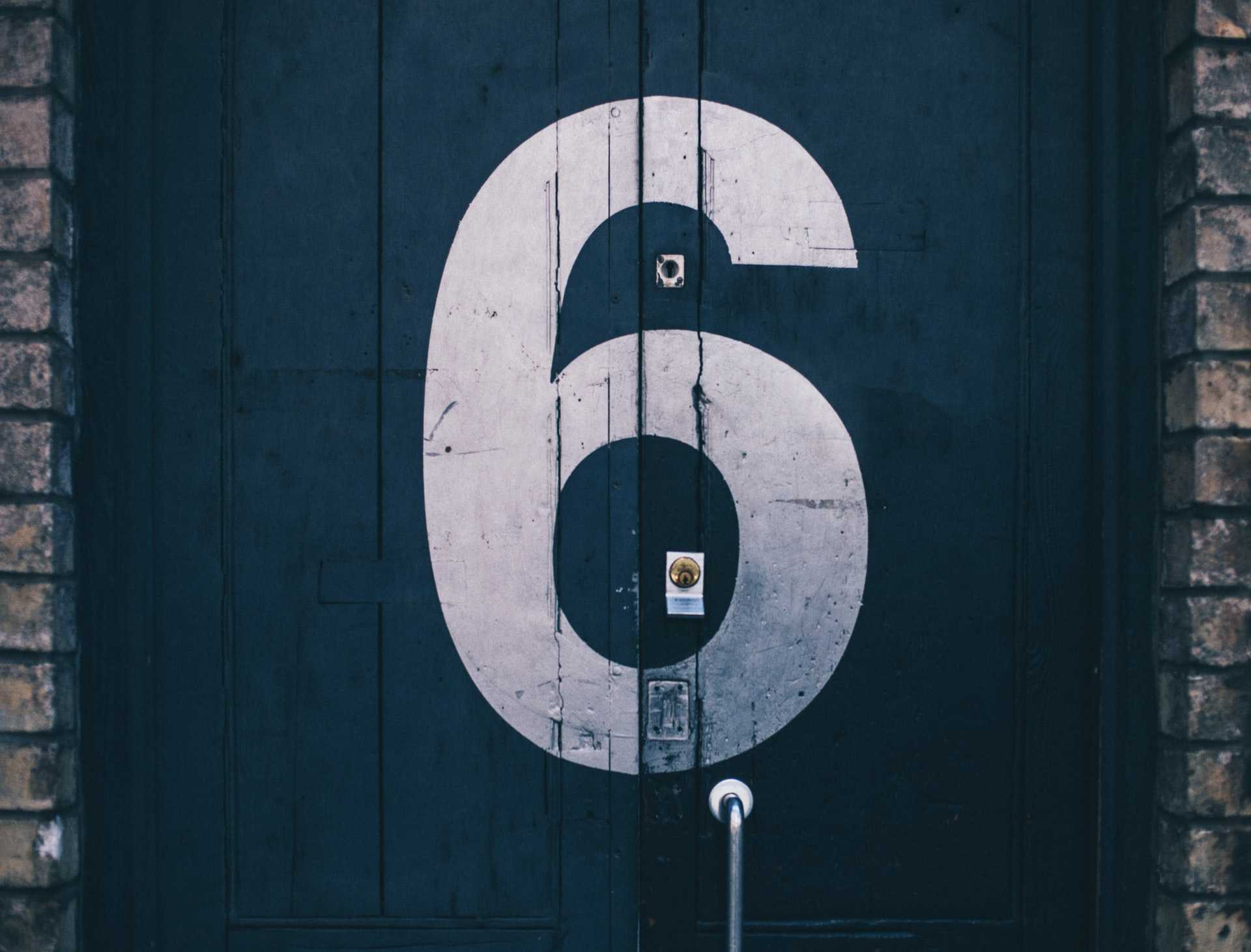 A garage door with a lock painted with the number 6.