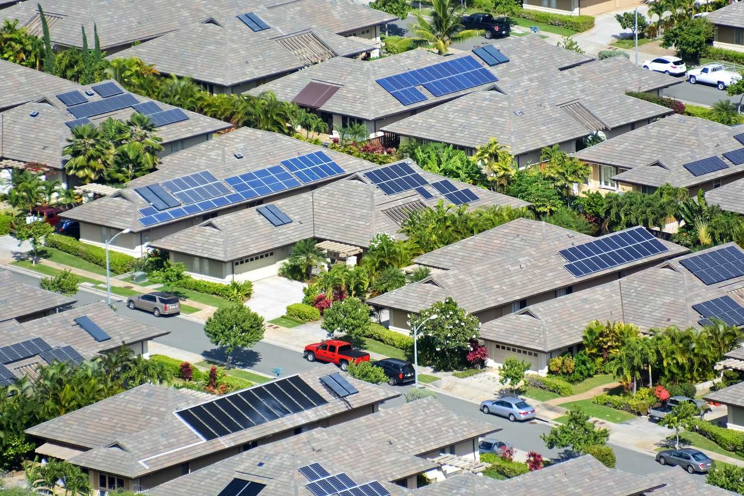 A neighborhood in Oahu, Hawaii with scattered solar panels on roofs of houses.